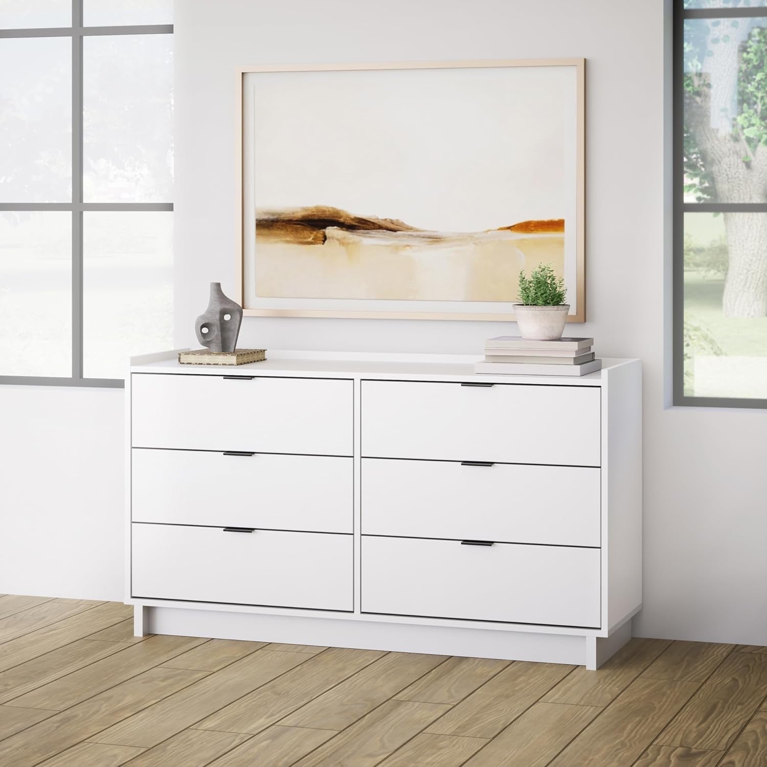 White dresser with decorative items in a room with a painting on the wall.