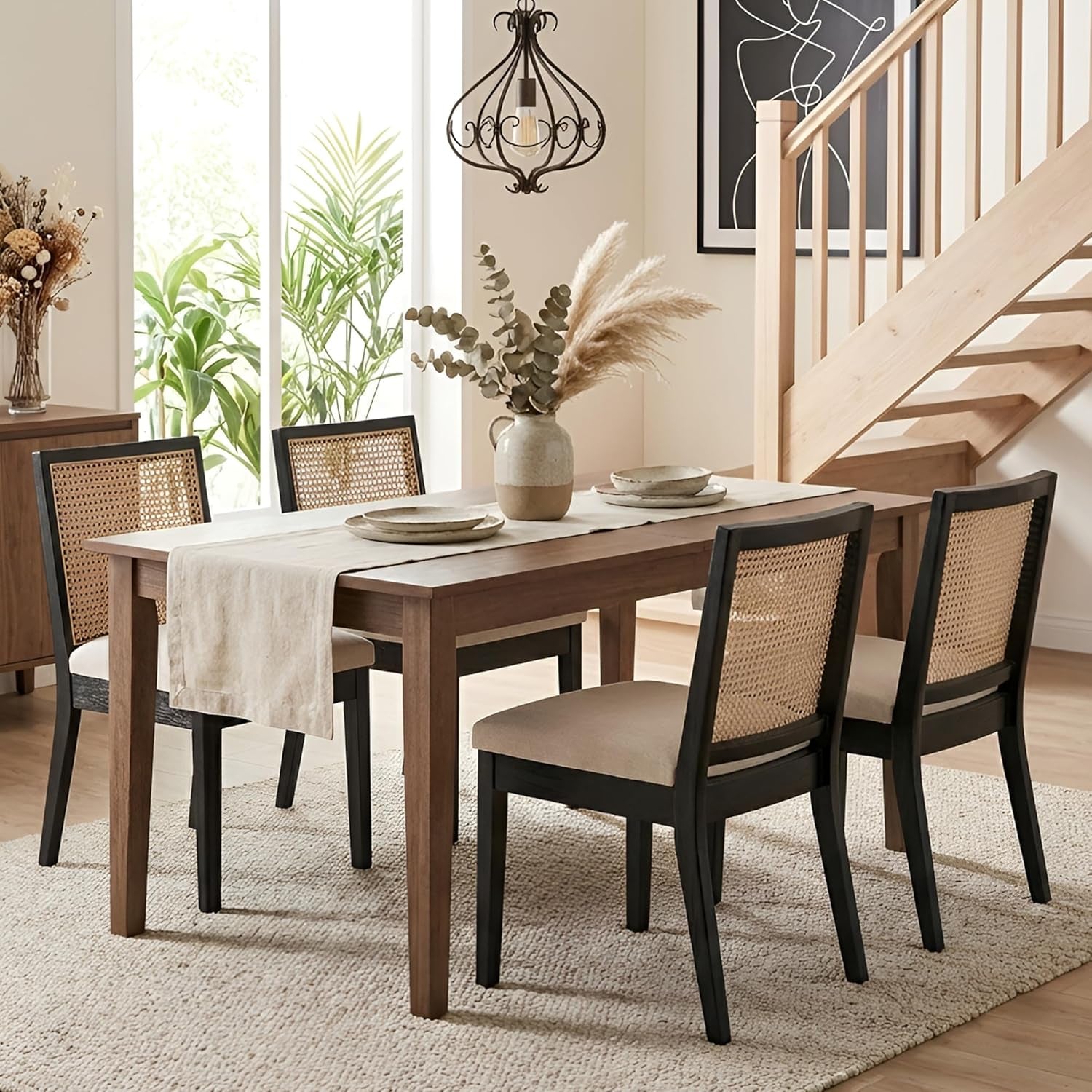 Dining room with wooden table and chairs, plants, and a staircase.