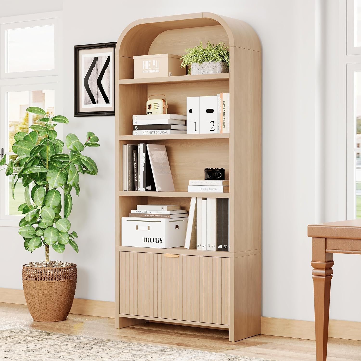 Wooden bookshelf with books and decor items in a room with a plant and table.