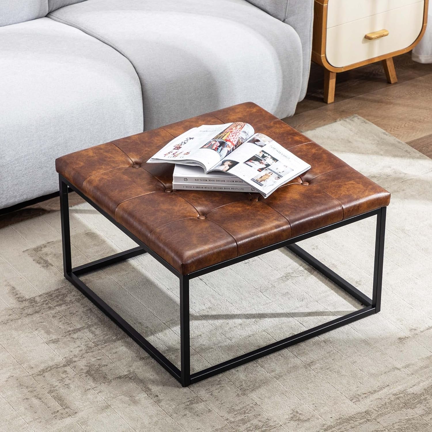 Brown leather coffee table with an open magazine in a living room setting.