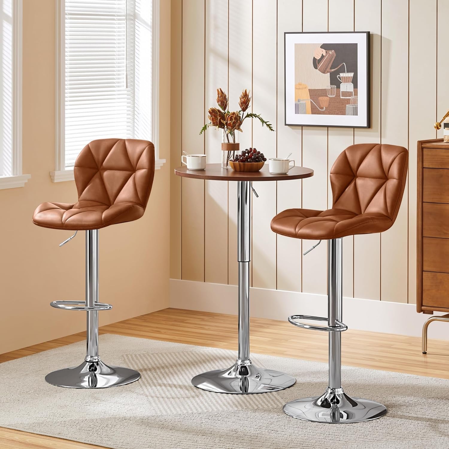 Two brown bar stools with a small round table in a room with a window and wall art.