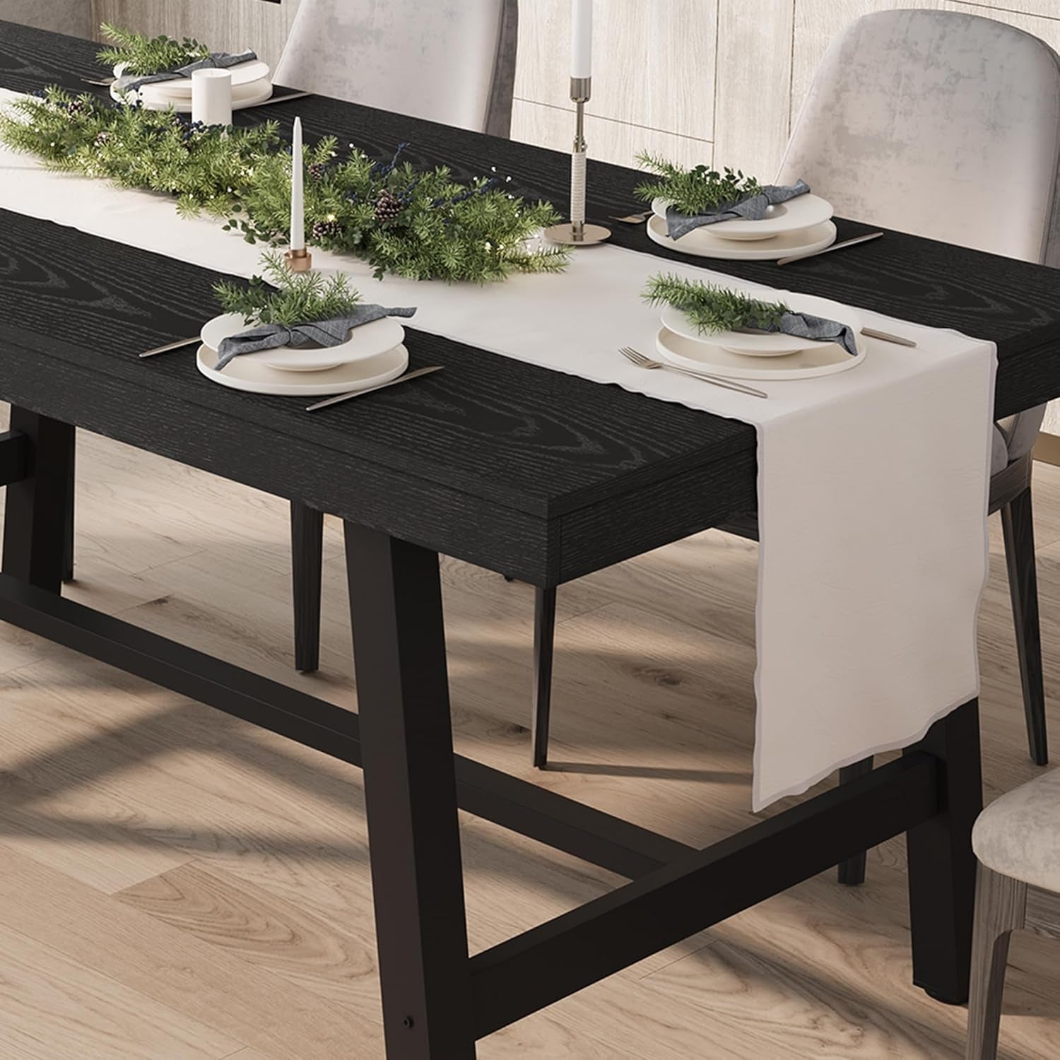Dining table set with black bench, white tablecloth, and greenery decorations.