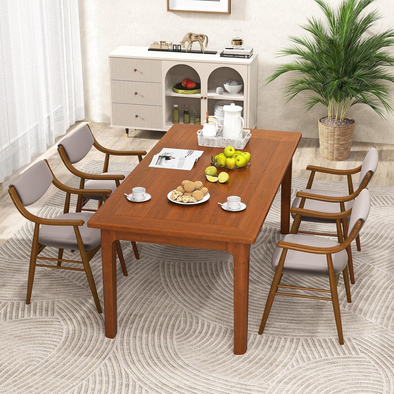 Dining room with wooden table and chairs, fruit on the table, and a cabinet in the background.