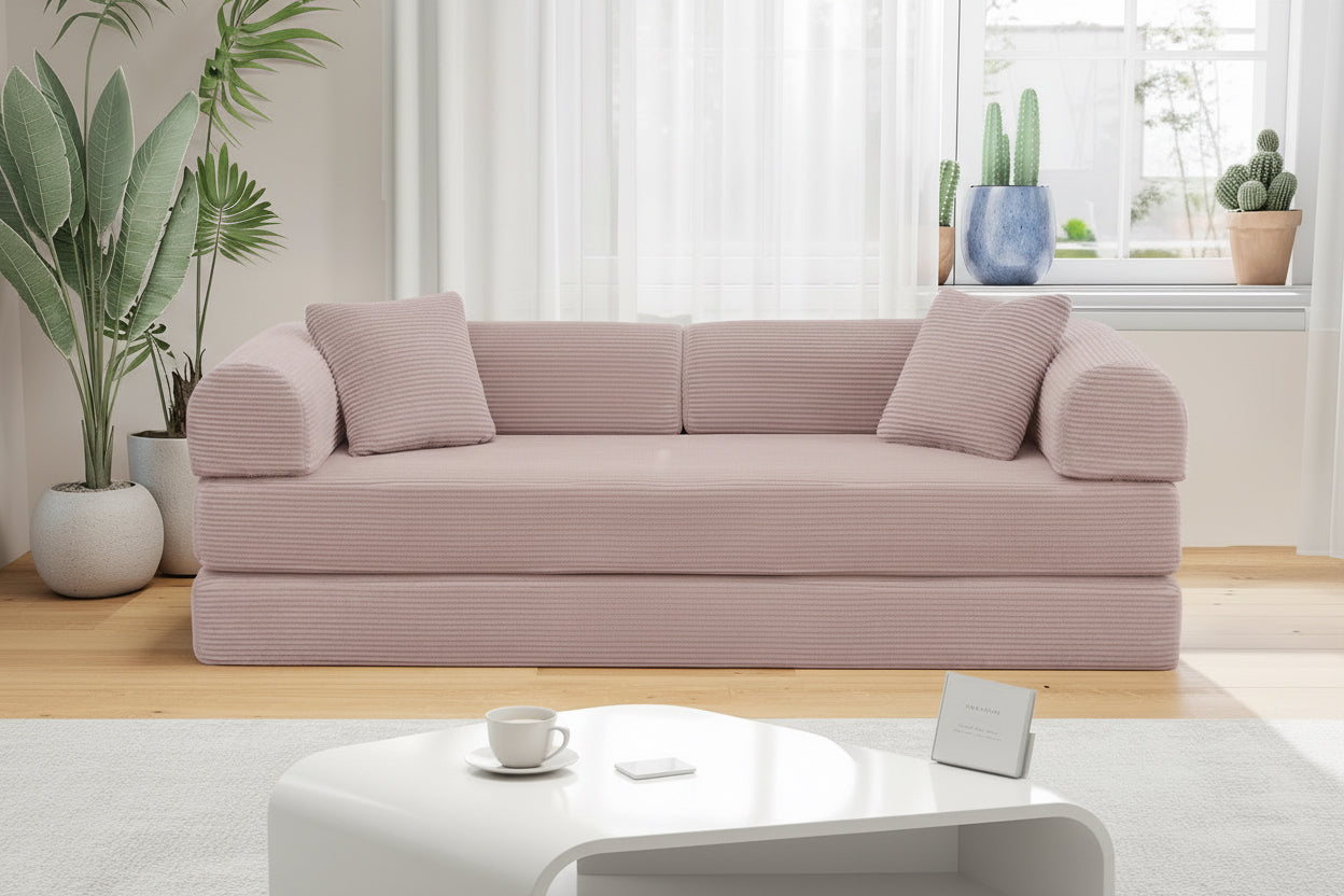 Woman using a laptop on a pink sofa in a bright living room with plants and a coffee table.