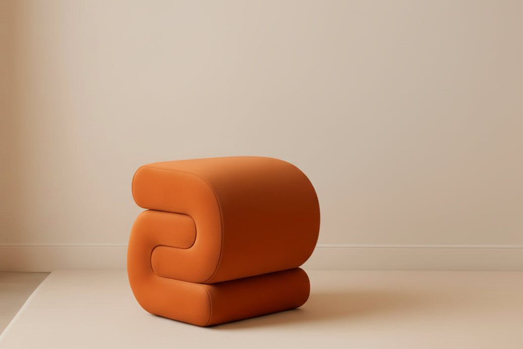 Orange modern chair in a room with a beige wall and side table.