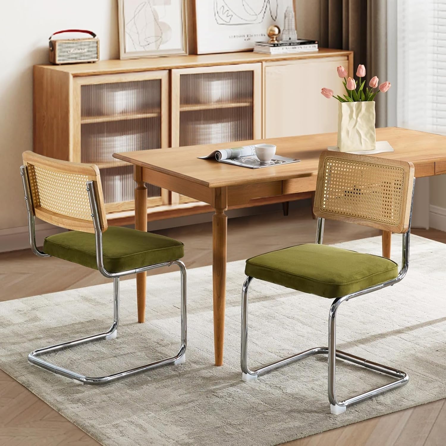 Wooden dining table with two chairs featuring green cushioned seats and metal frames, in a room setting.