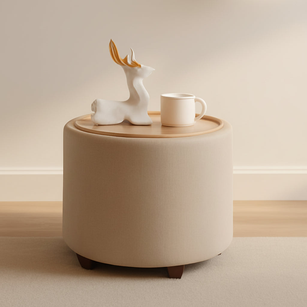 Round beige ottoman with a decorative deer figure and white mug on top, against a warm-toned wall.