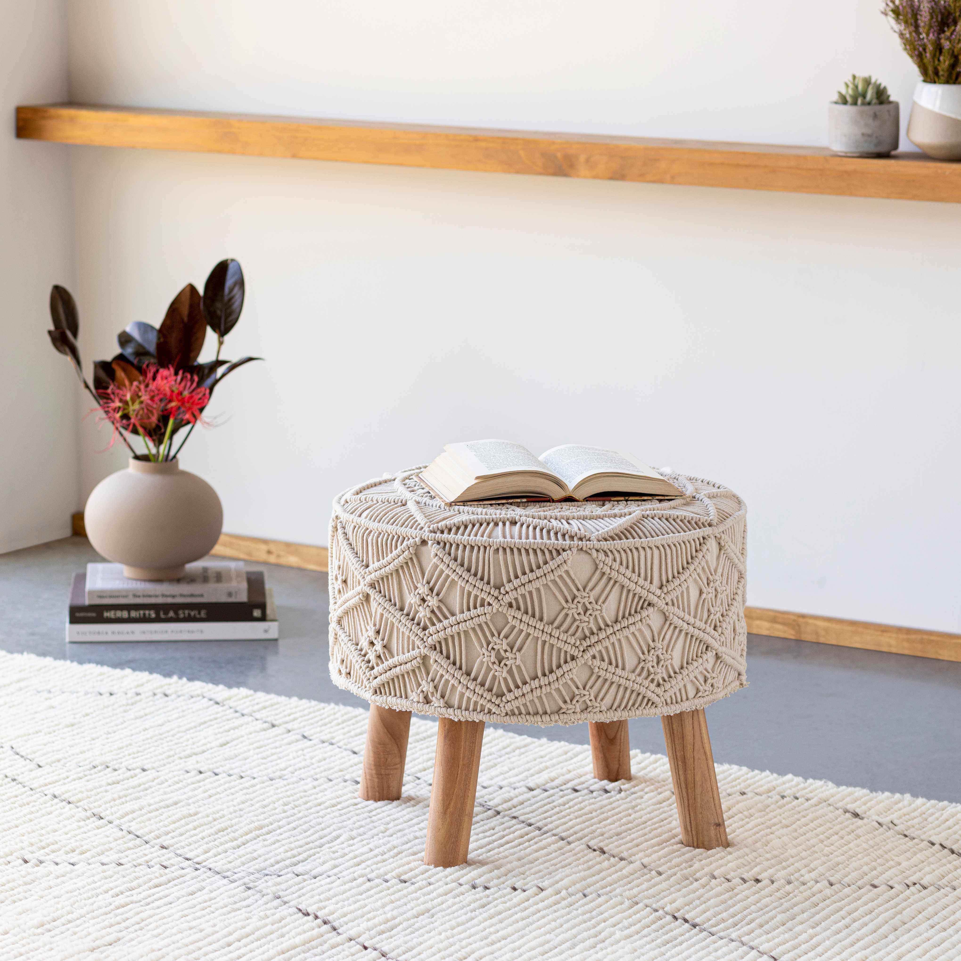 Woven stool with wooden legs in a room with a shelf and plants.