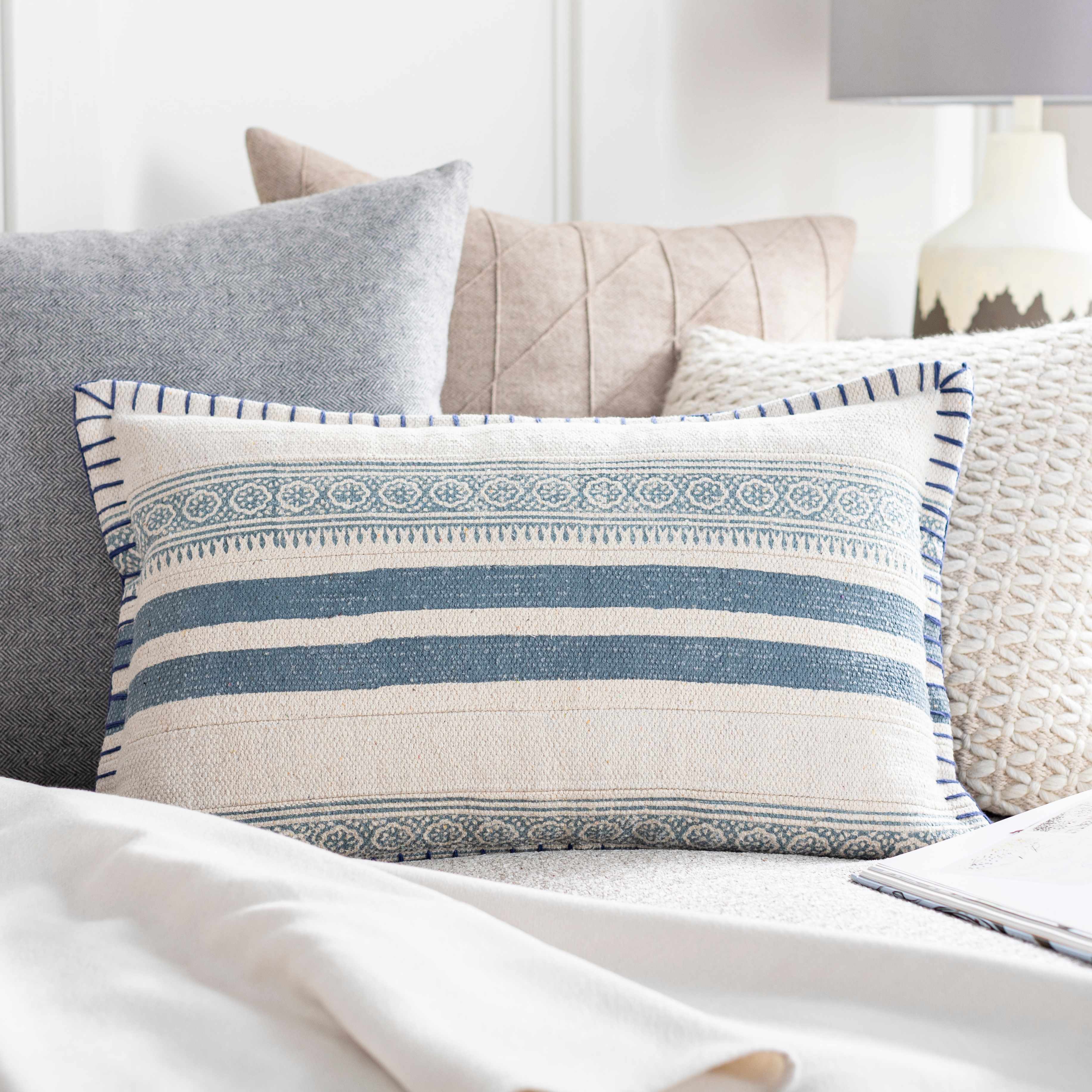 Decorative pillow with blue and beige stripes on a bed