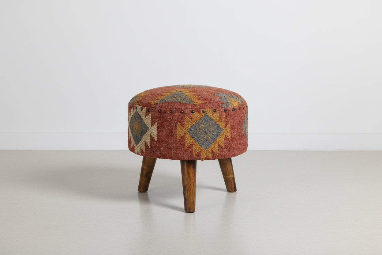Round ottoman with patterned fabric and wooden legs on a white background