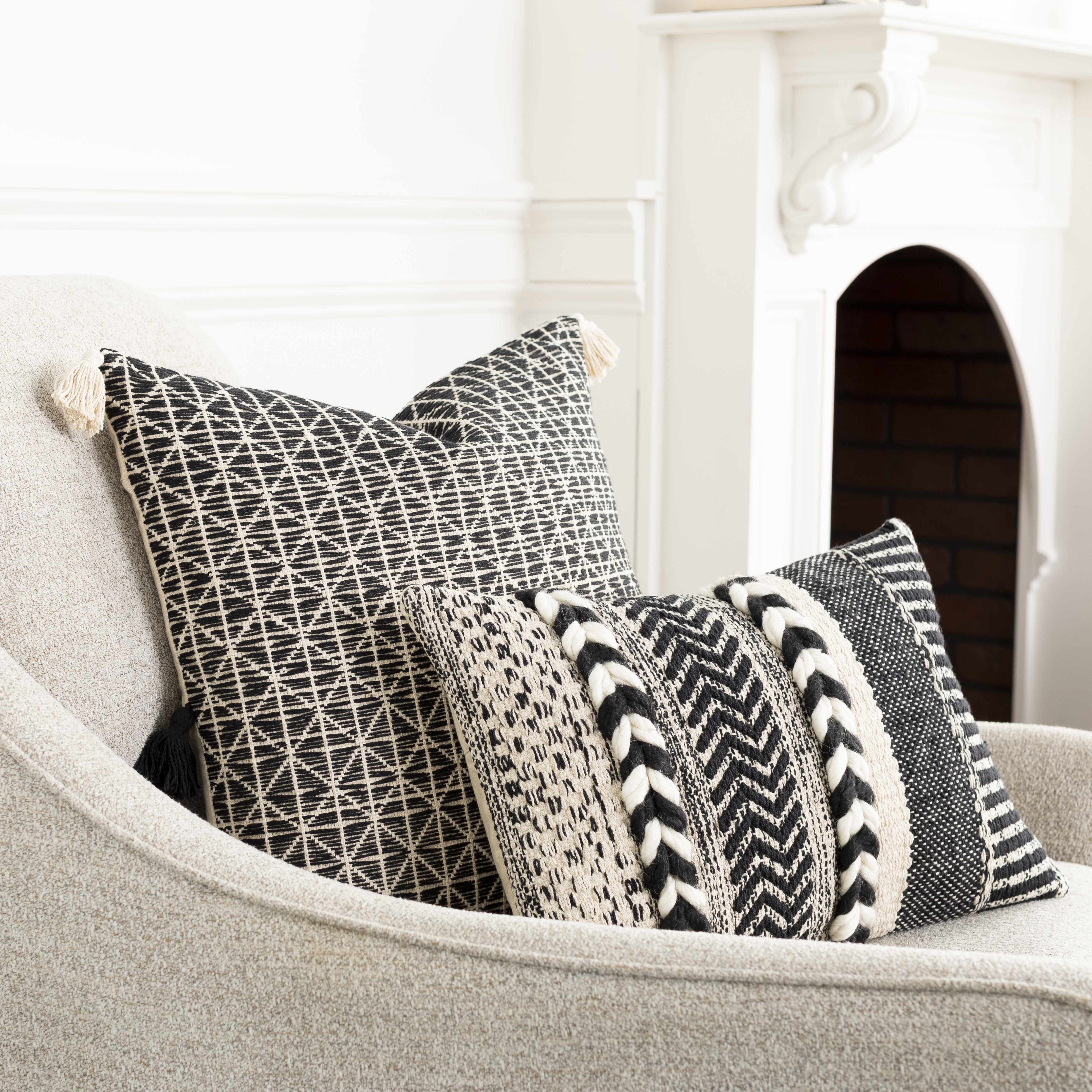 Two patterned pillows on a gray sofa with a white fireplace in the background
