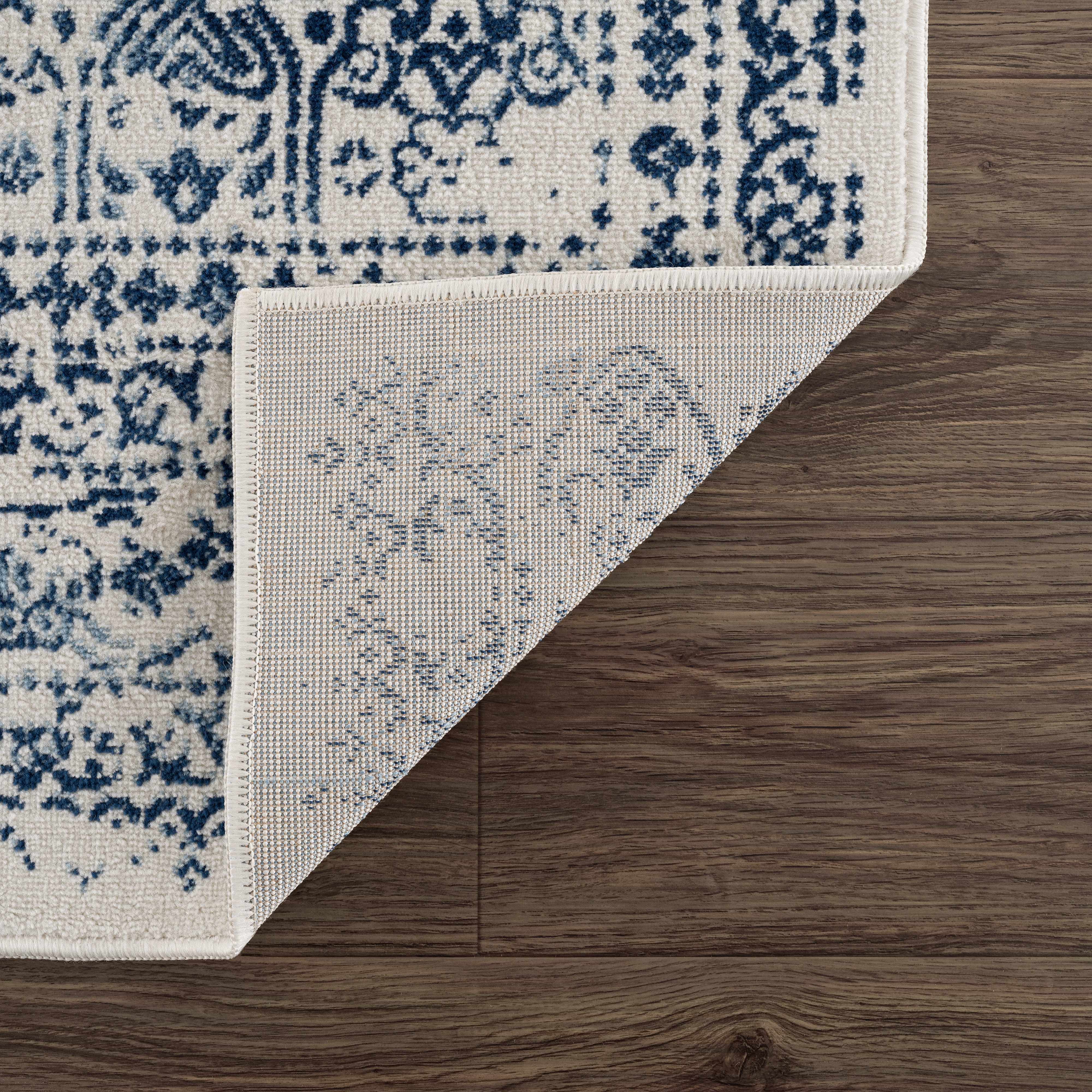 Corner of a blue and white patterned rug on a wooden floor