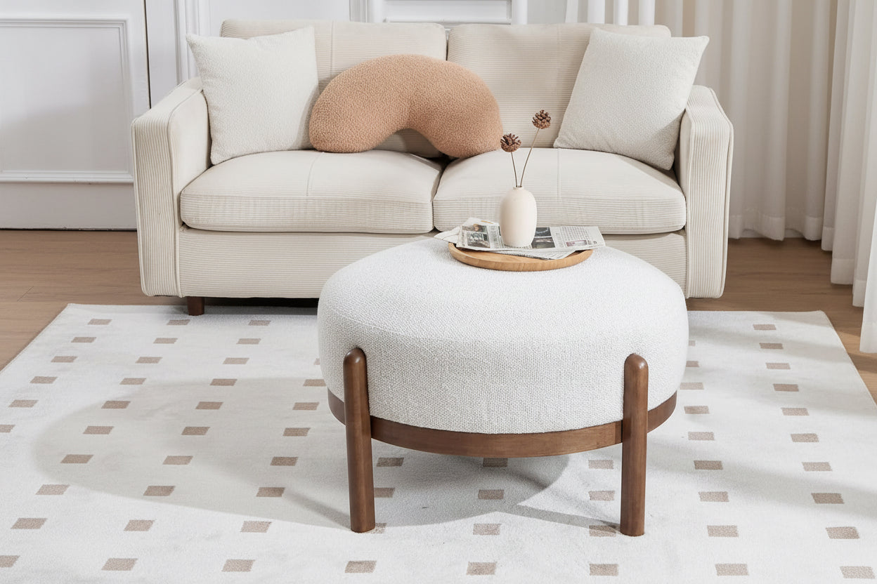 White ottoman with wooden legs in a living room setting, featuring soft sherpa fabric and high-density sponge.
