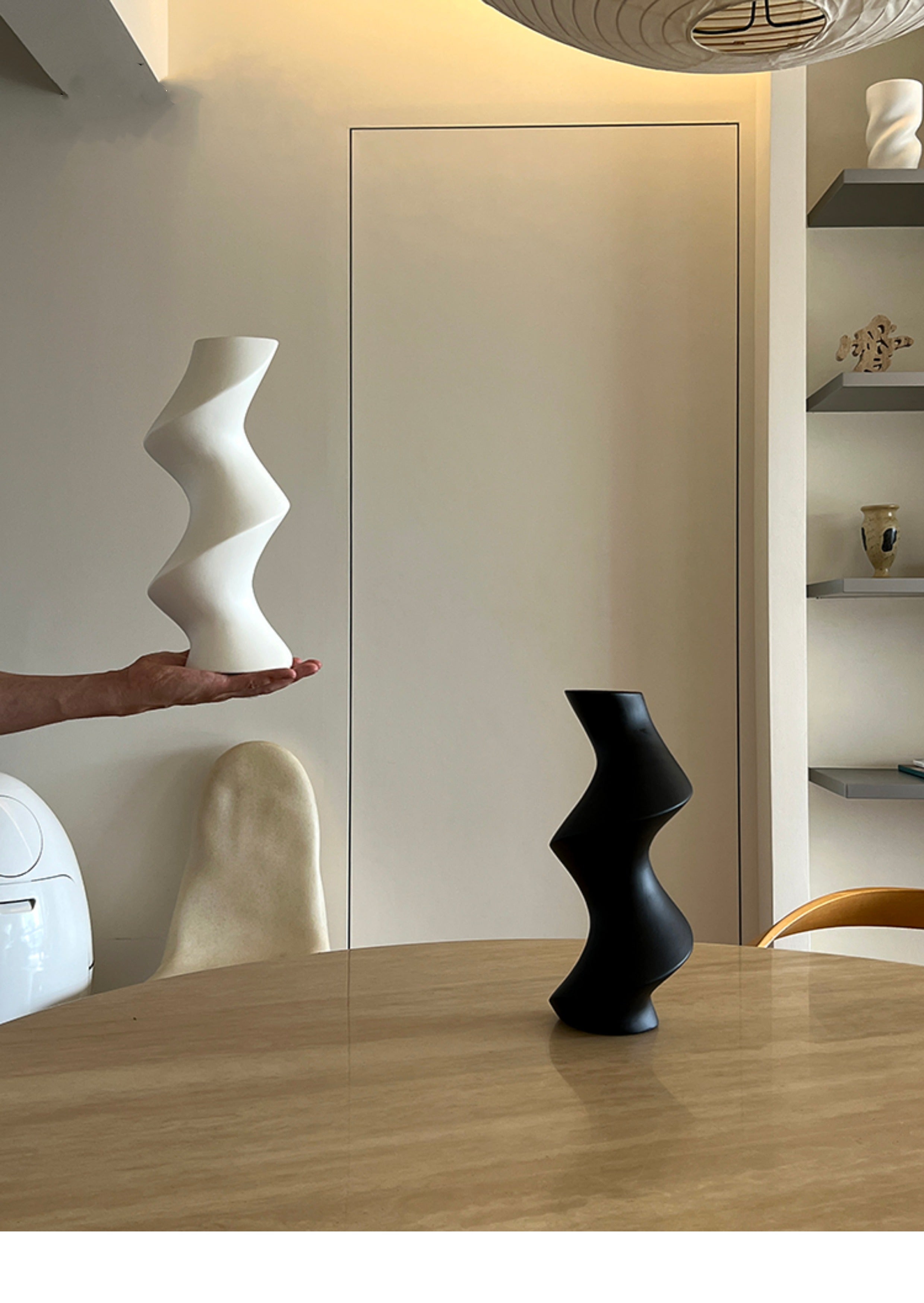 White and black abstract vases on a wooden table with a neutral background