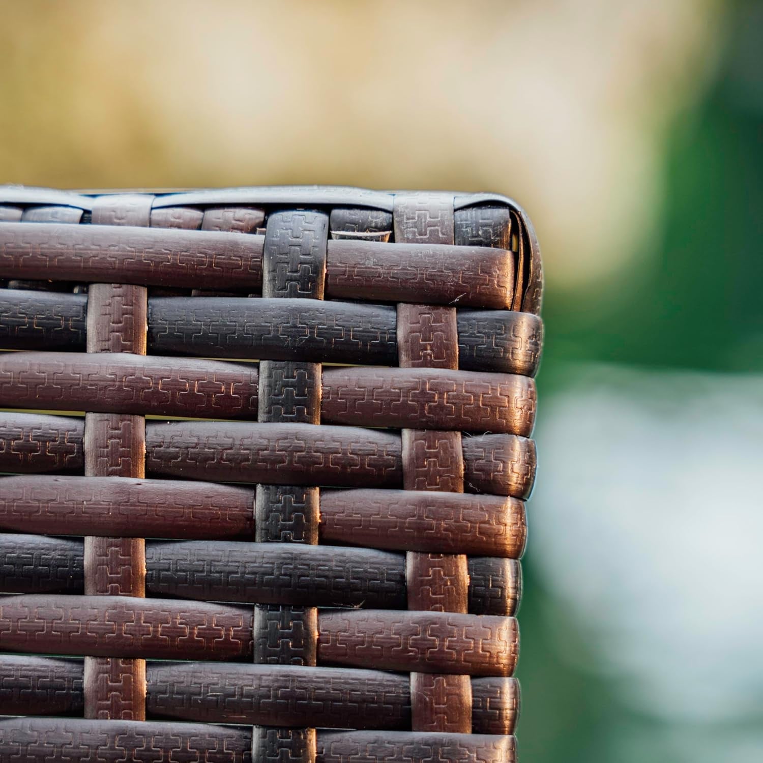 Close-up of woven brown chair back with blurred green background