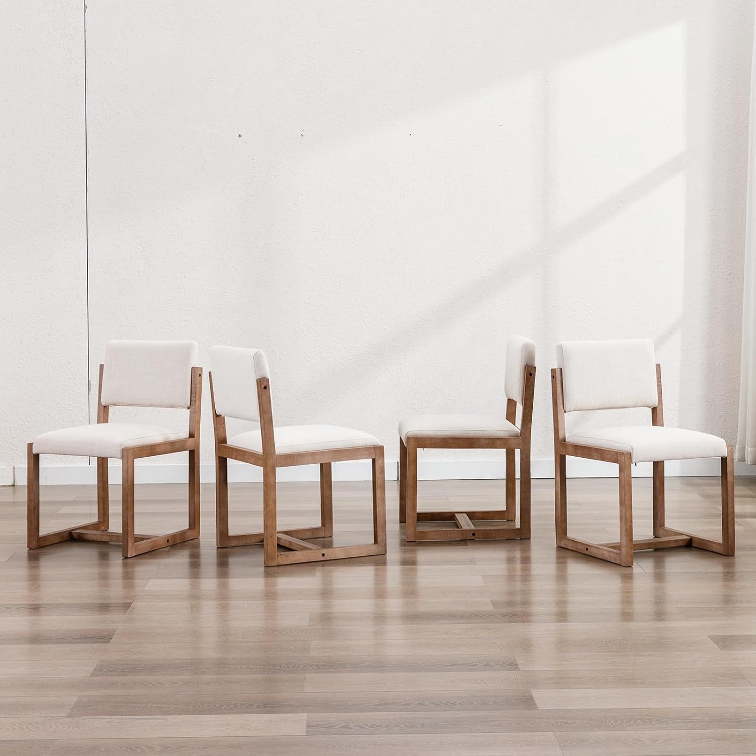  wooden chairs and white cushions in a bright room.