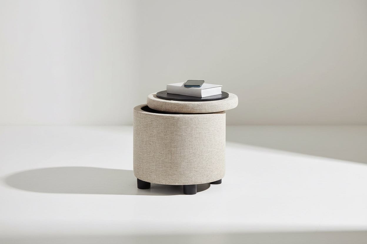 Round storage ottoman with a black top holding books and a phone on a white background