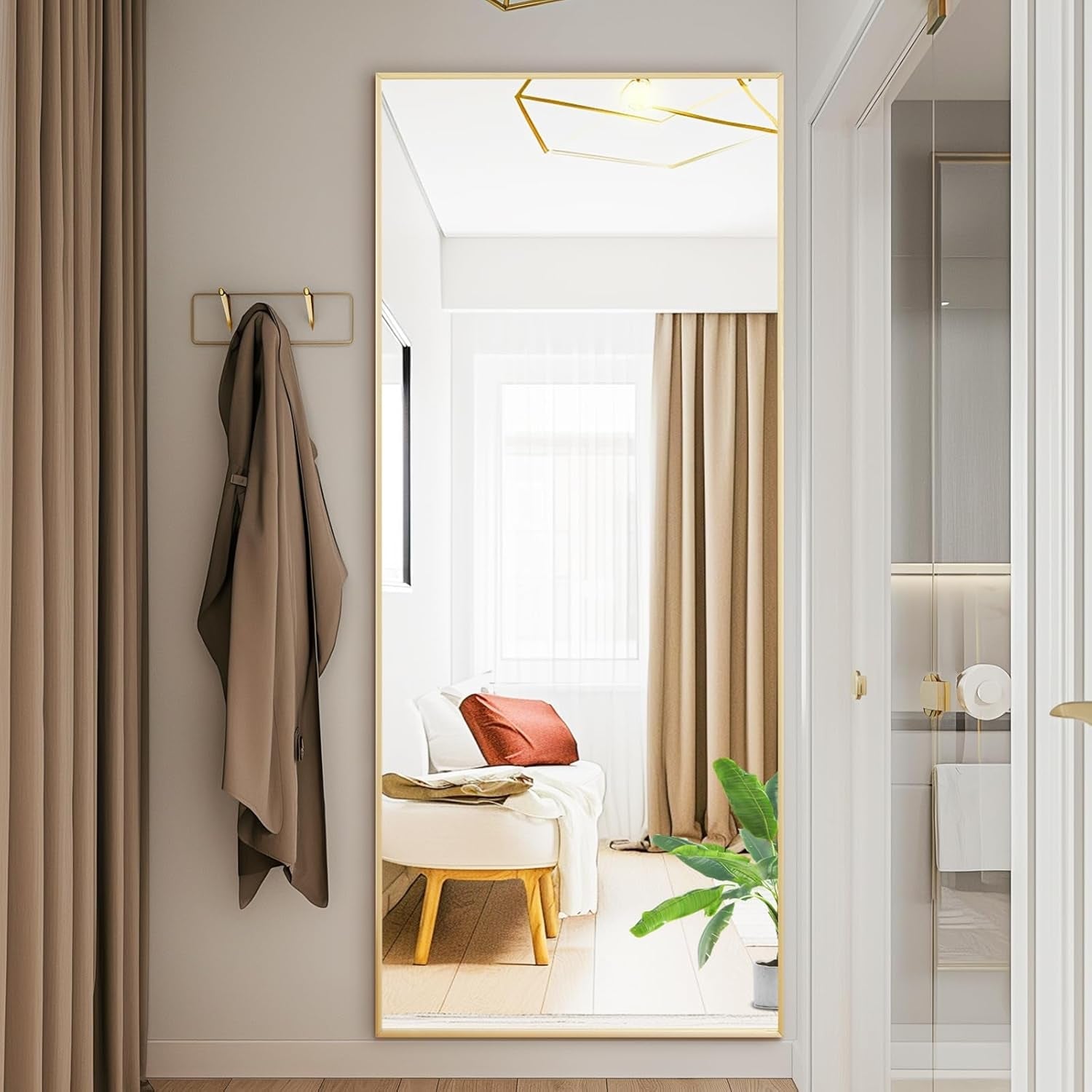 Full-length mirror in a room with a coat hanging on a hook and a view of a bed and window.