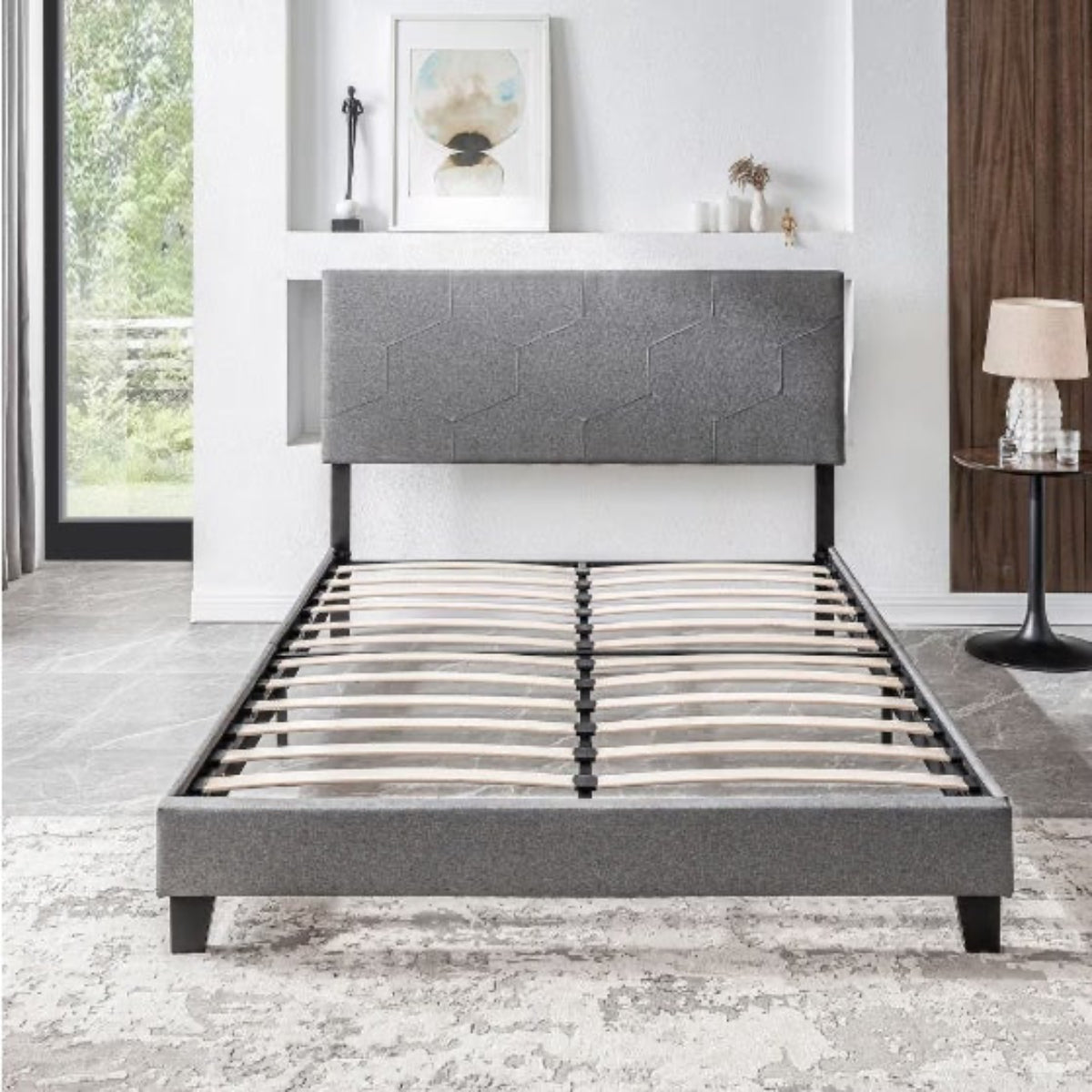 Gray upholstered bed frame in a modern bedroom setting with decor elements.