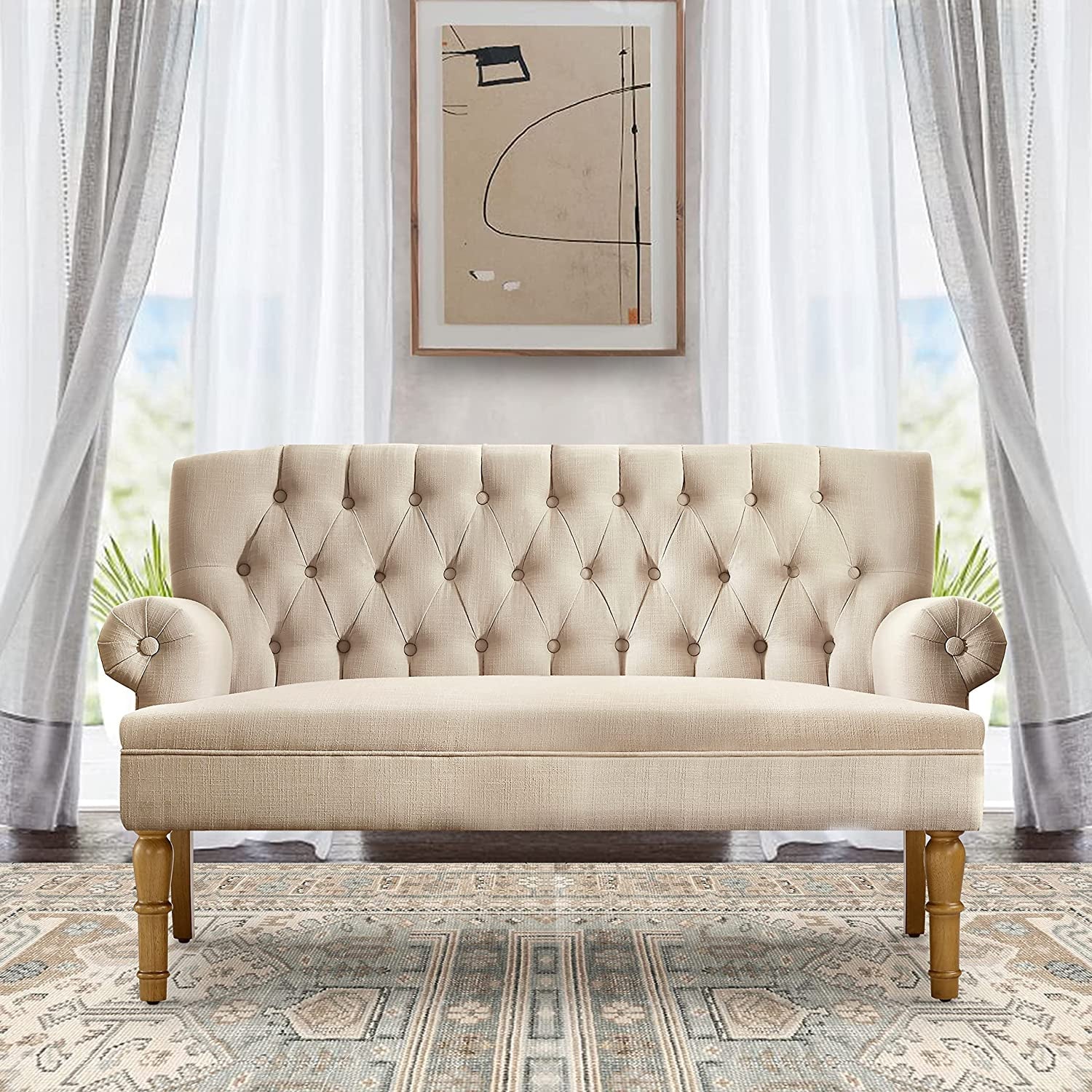 Beige tufted sofa in a room with large windows and abstract art on the wall.