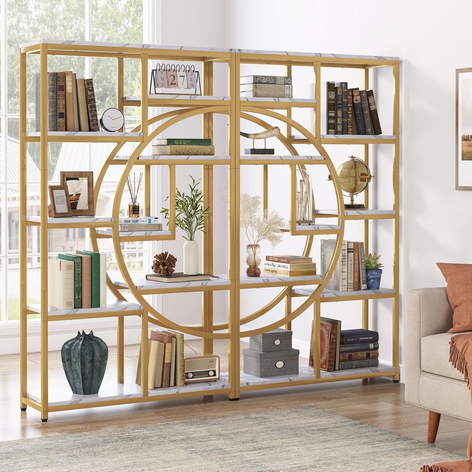 Gold circular bookshelf in a living room with books and decor items.
