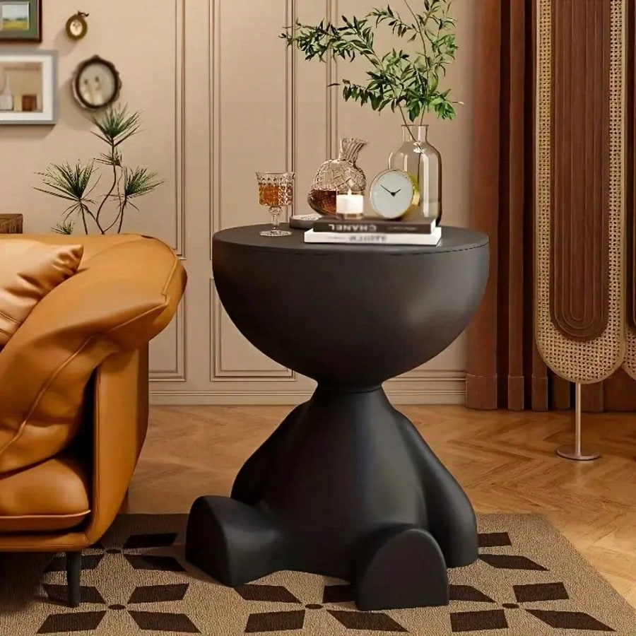 Modern black side table in a living room setting with decor items.