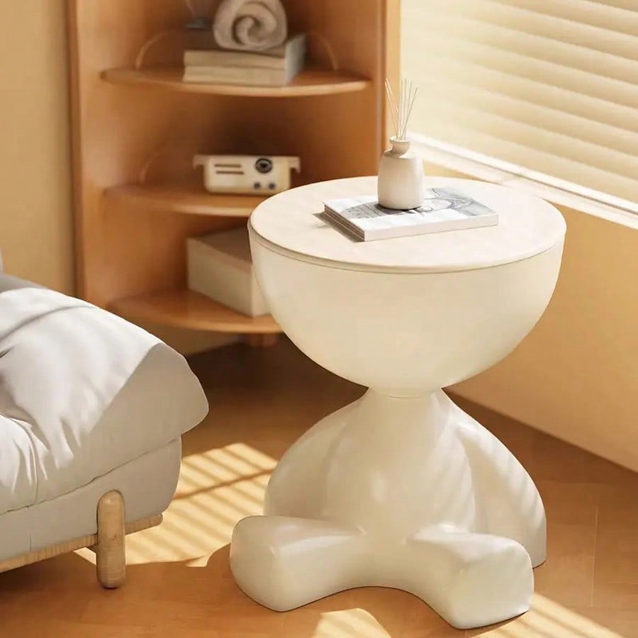White side table in a room with wooden shelves and a window.