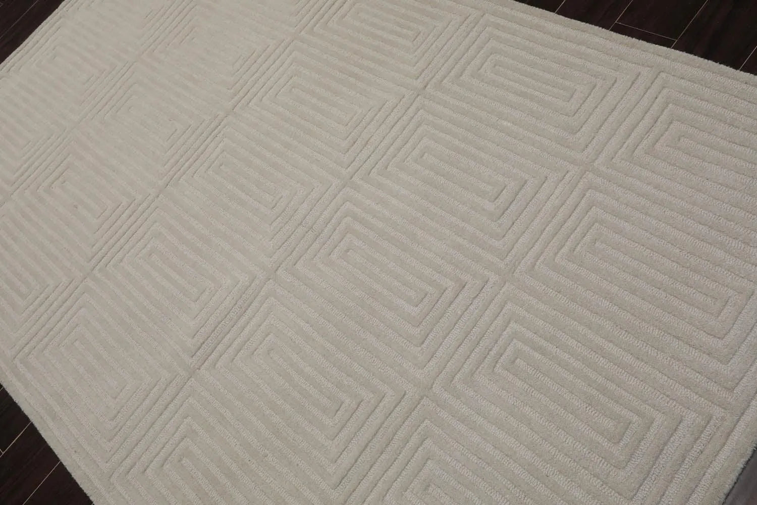 Close-up of a textured gray rug with geometric pattern on a wooden floor.