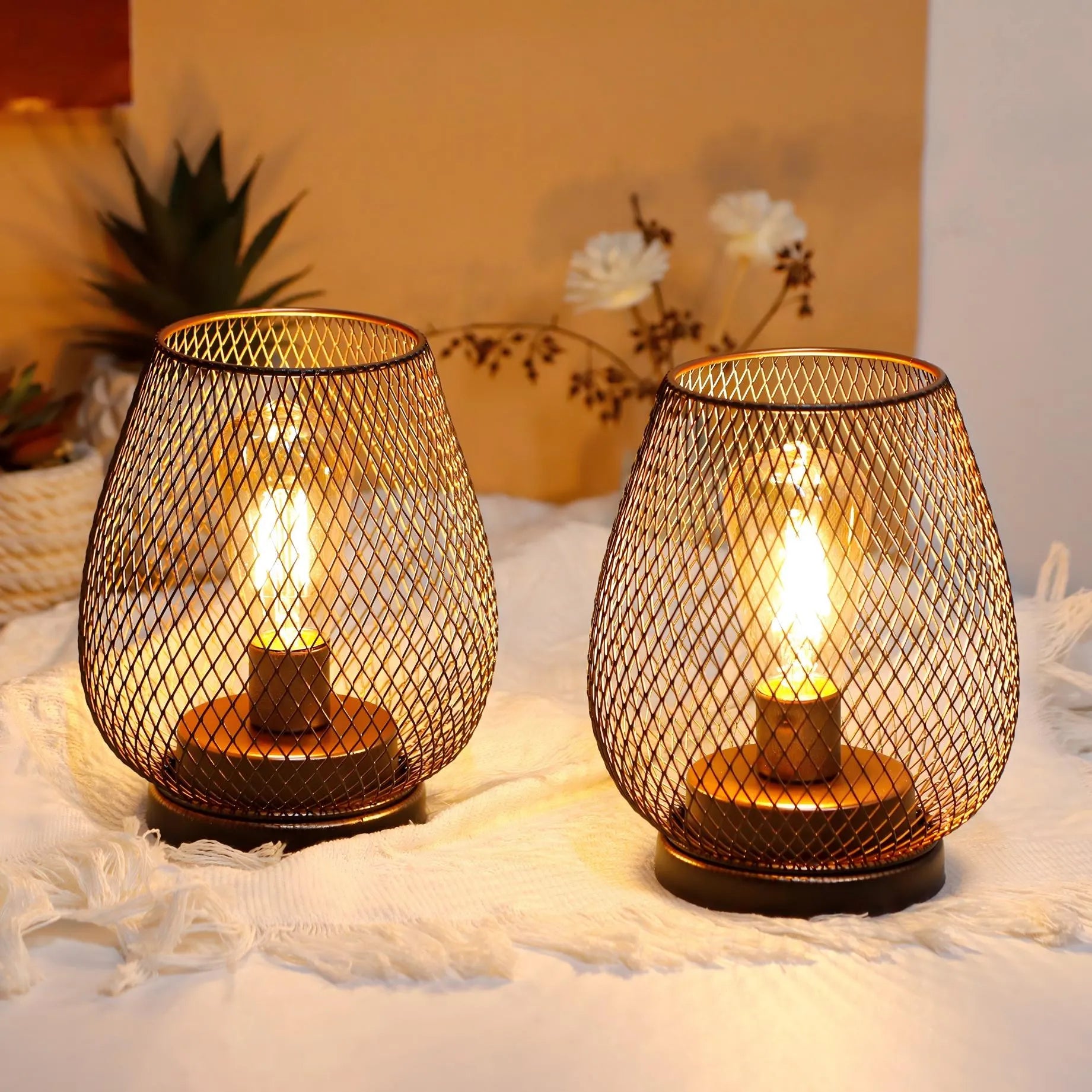 Two mesh-wrapped table lamps with lit bulbs on a soft surface.