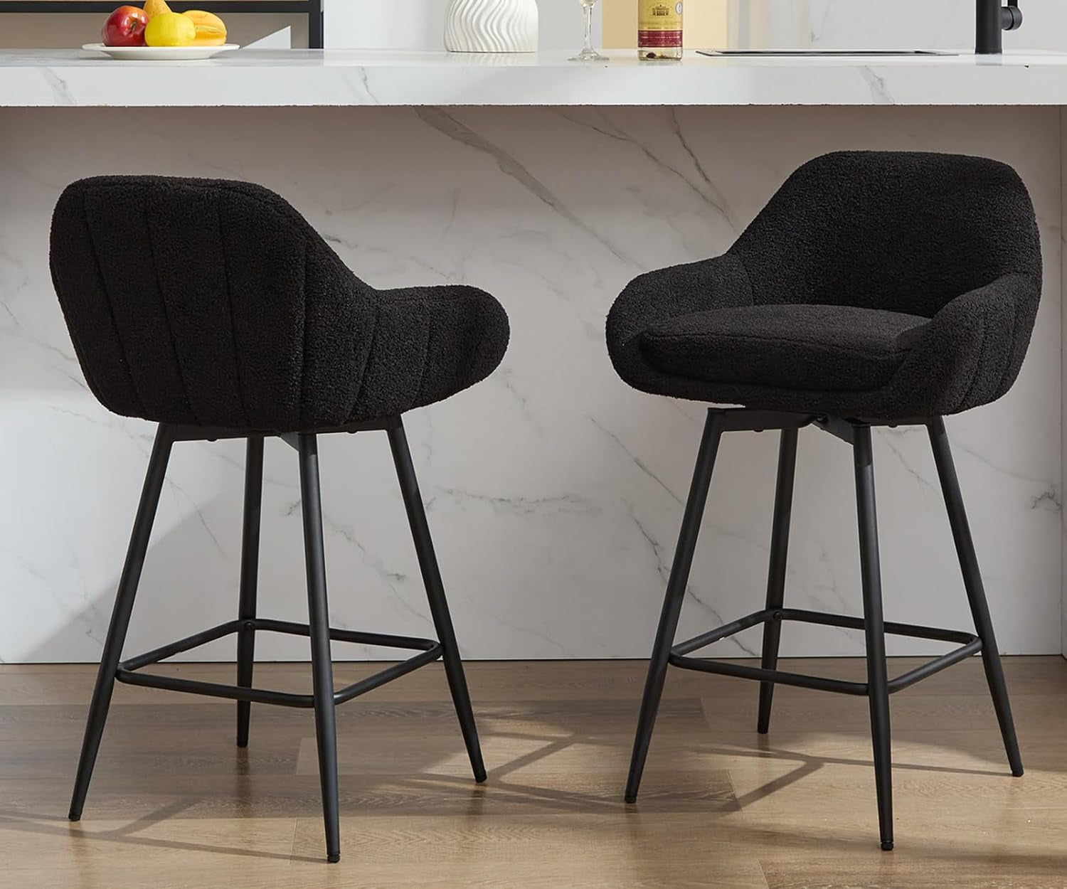 Two black bar stools in a kitchen setting with a marble countertop.