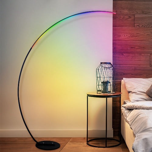 Arc-shaped LED floor lamp with colorful light in a bedroom setting.