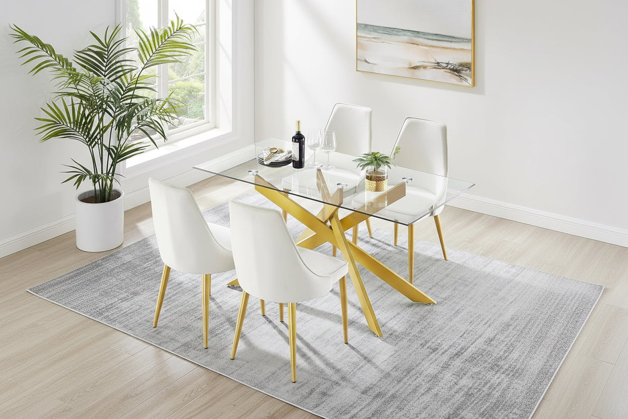 Dining table with gold legs and white chairs in a bright room.