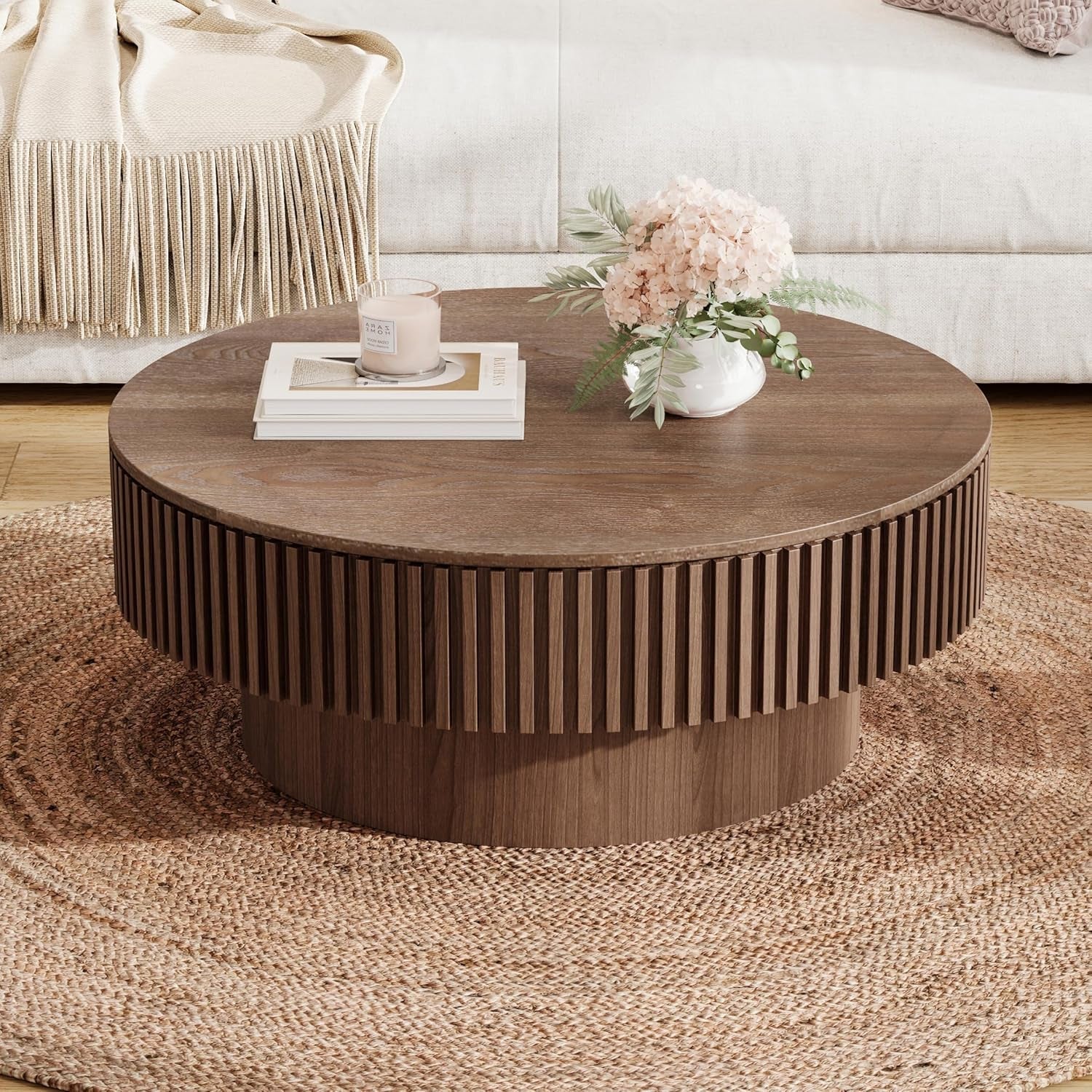 Round wooden coffee table with decorative items in a living room setting