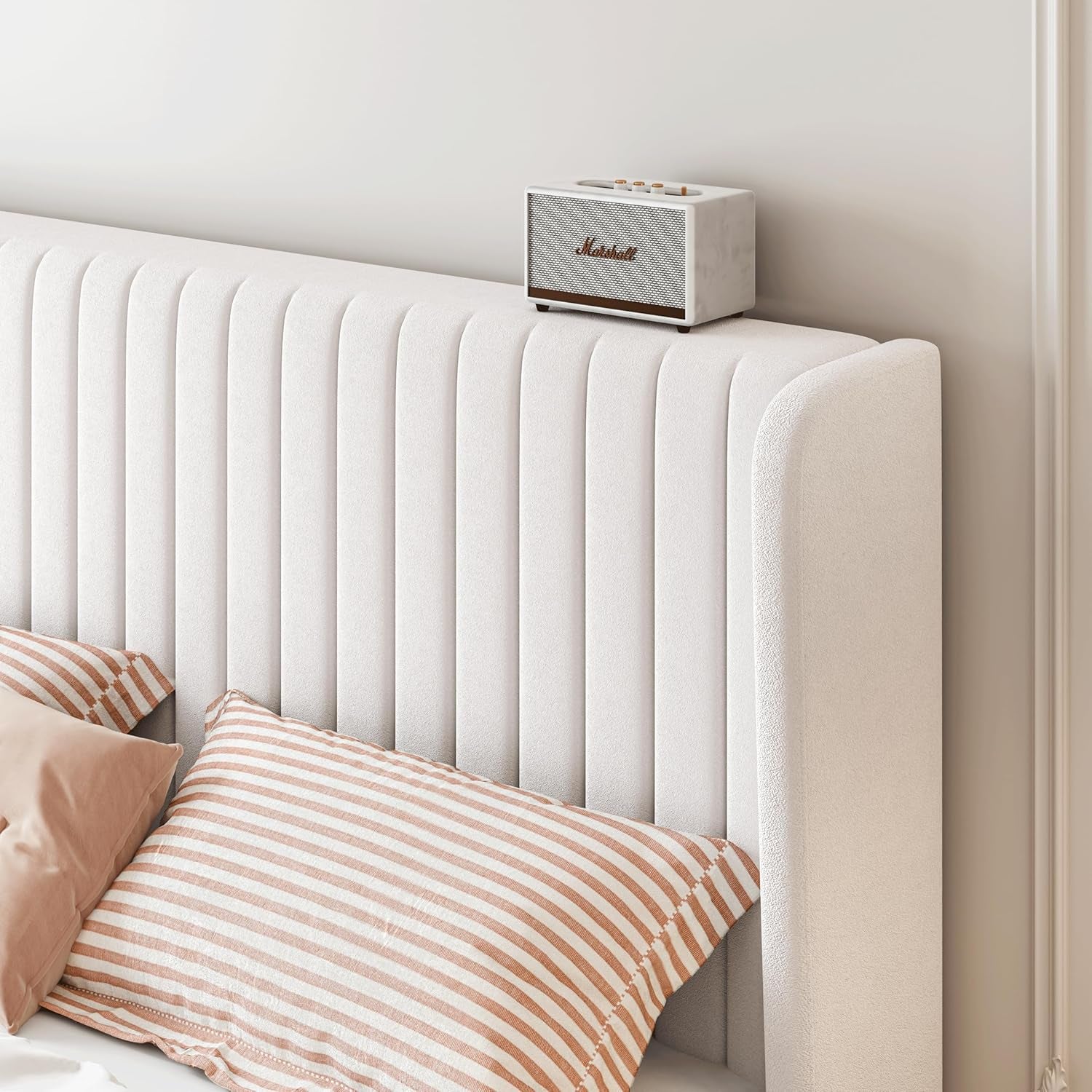 Marshall speaker on a white upholstered headboard with striped pillows.