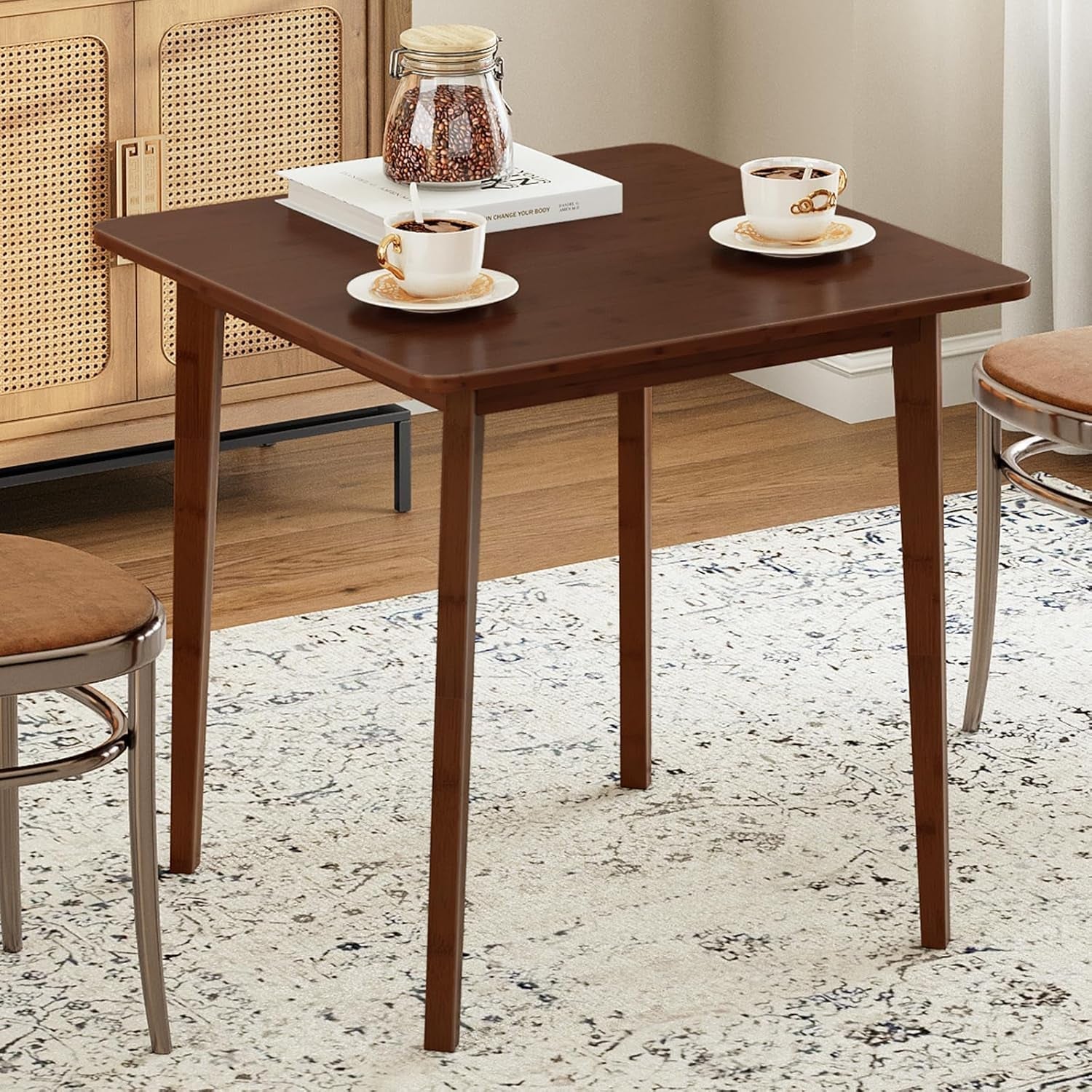 Wooden dining table with two chairs and coffee cups on a patterned rug