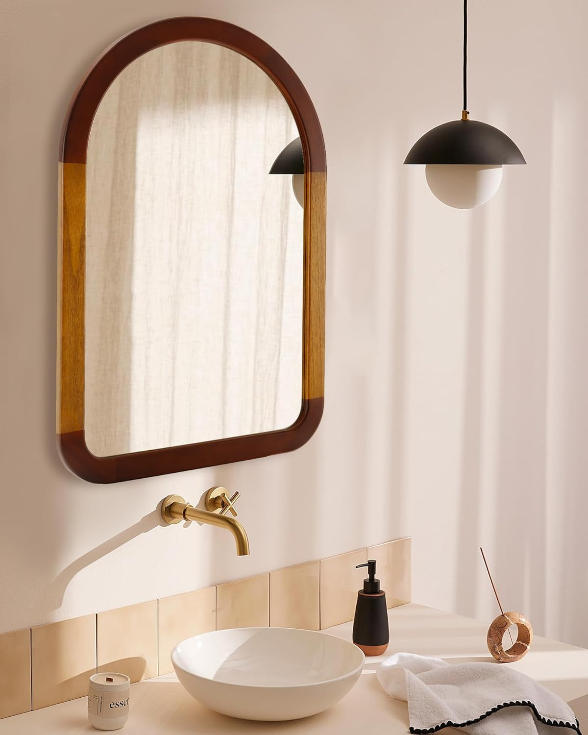 Bathroom with a wooden-framed mirror, white sink, and gold faucet.