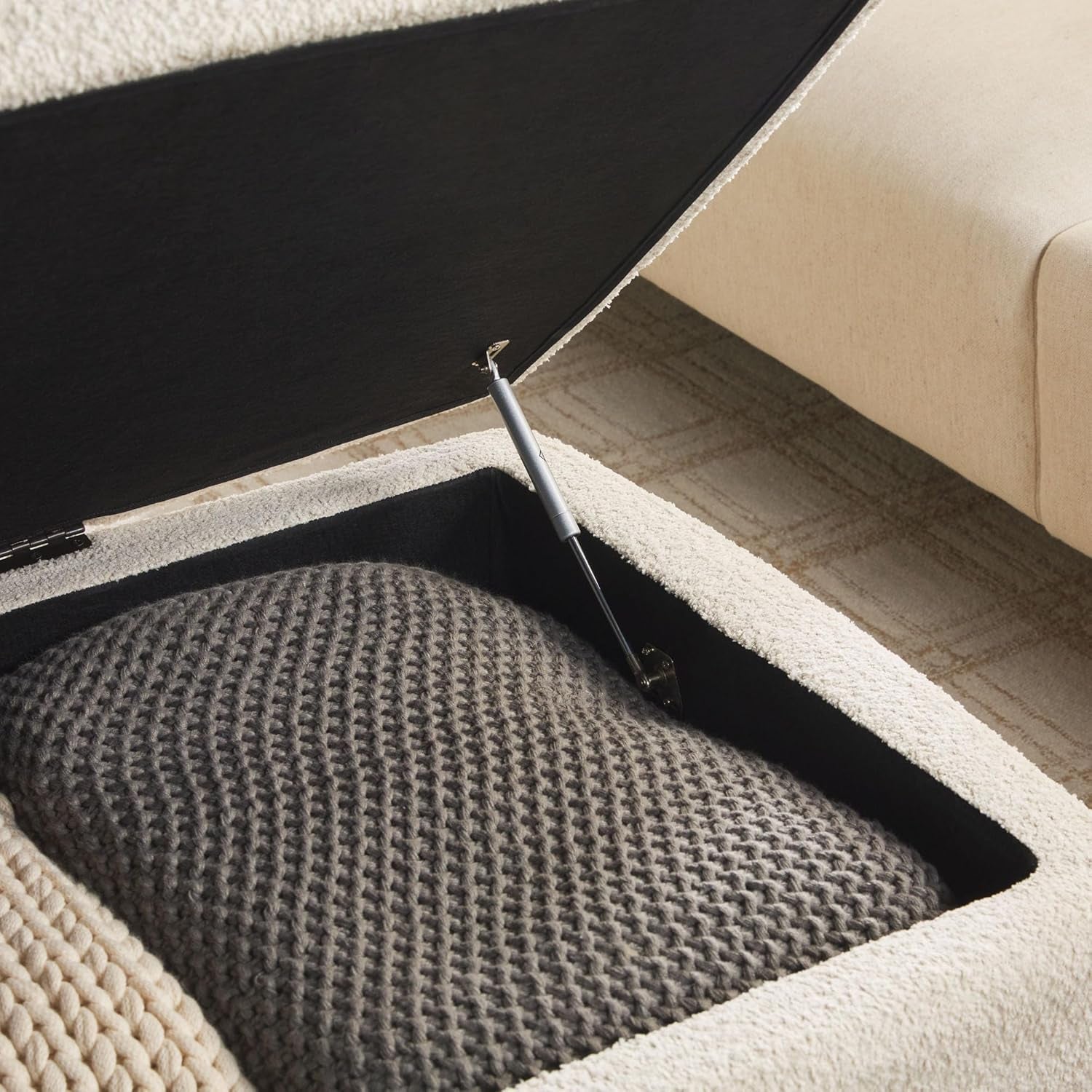 Section of a sofa with a textured gray cushion and a black ottoman underneath.