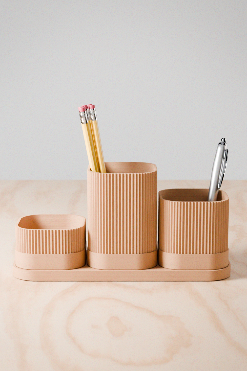 Set of beige desk organizers with pencils and pens on a wooden surface.