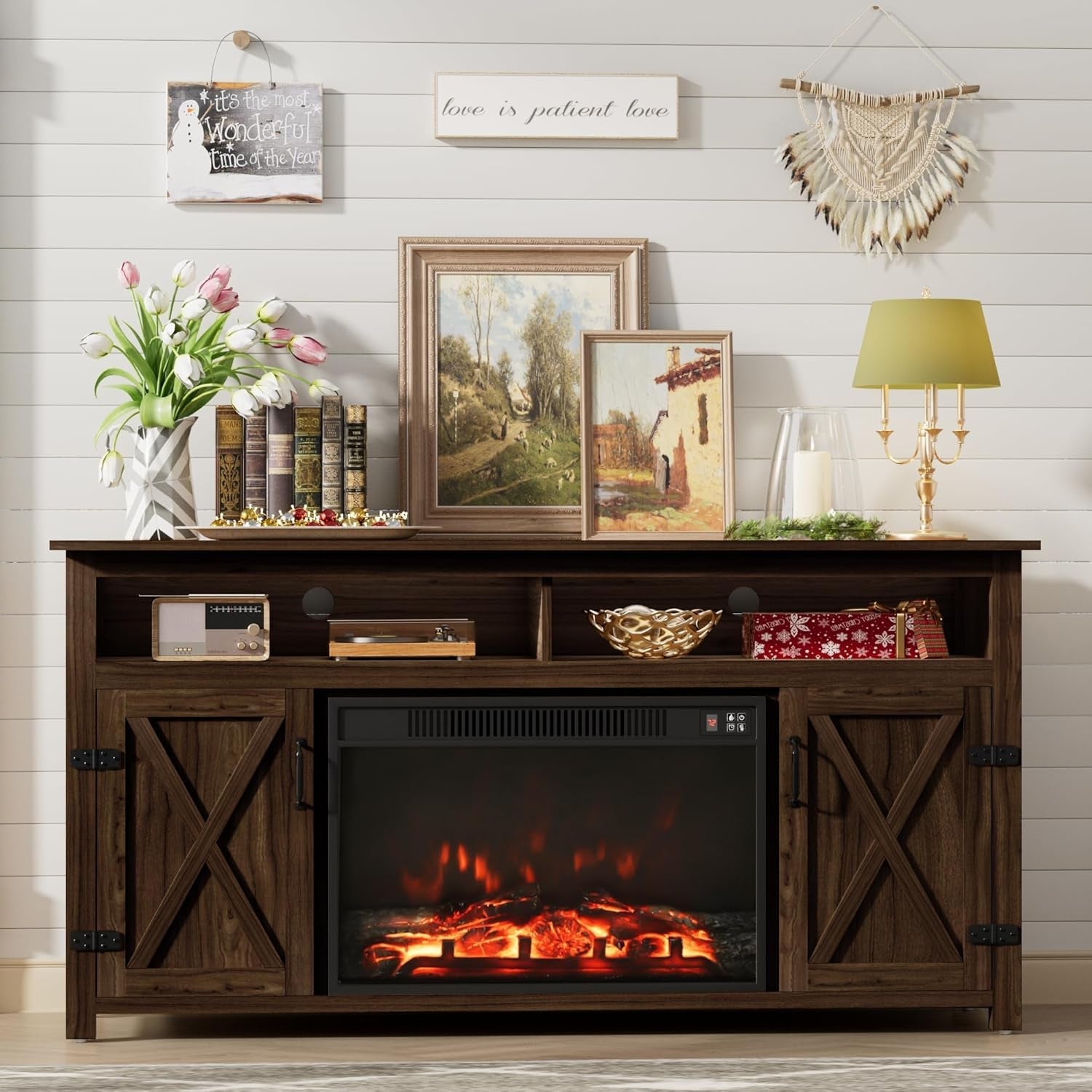 Wooden entertainment console with electric fireplace, books, and decorative items against a white wall.