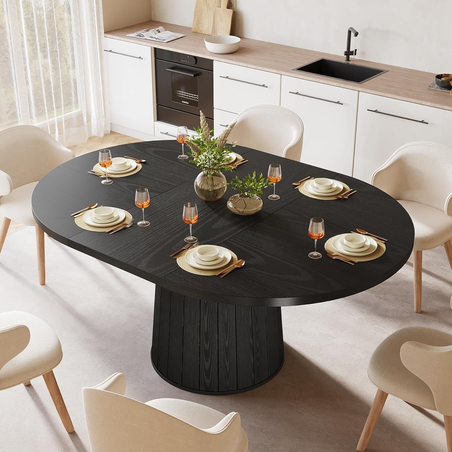 Black round dining table set with white chairs in a modern kitchen.