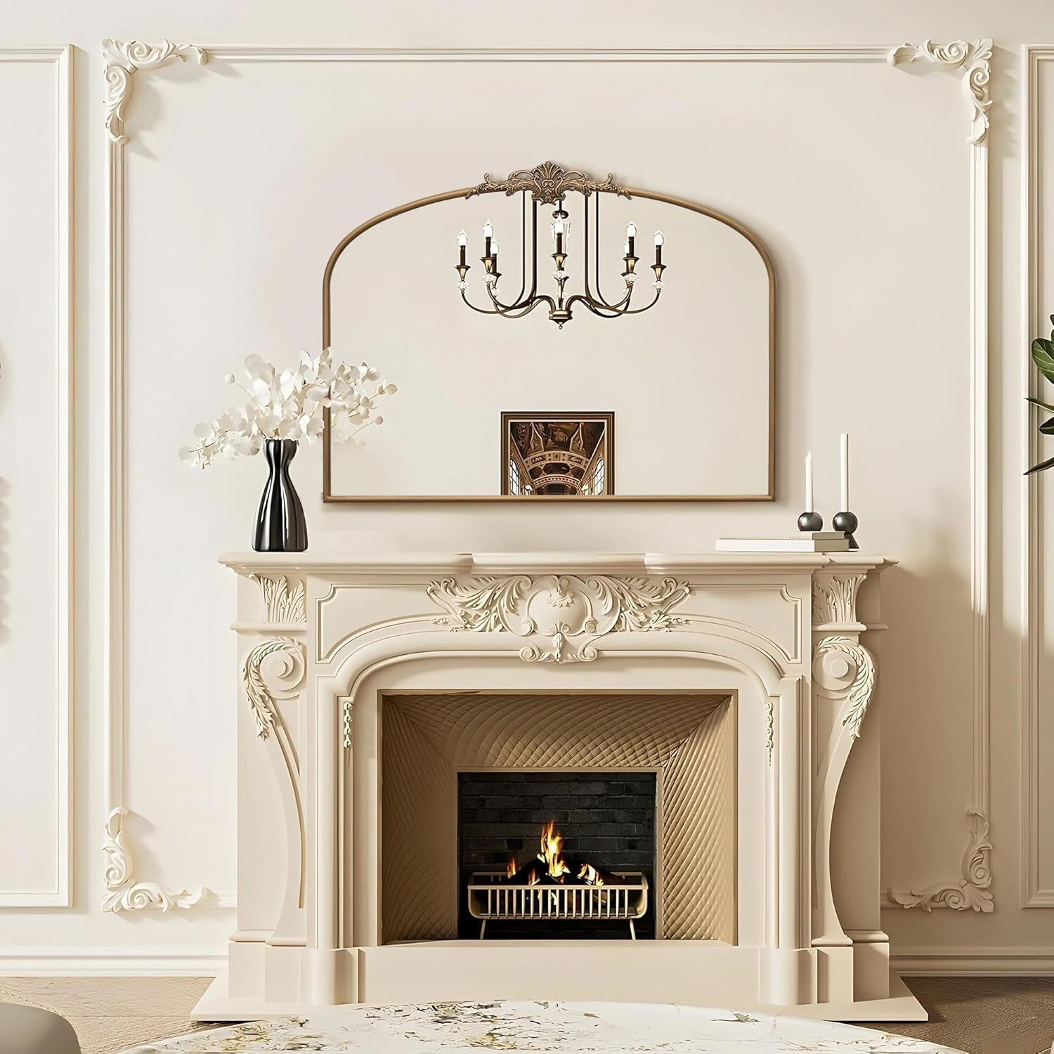 Decorative fireplace with mantel, mirror, and chandelier in a room with white walls.