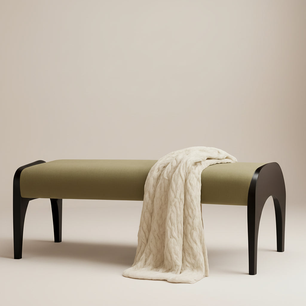 Beige bench with a white blanket draped over it in a room with a lamp on a side table.