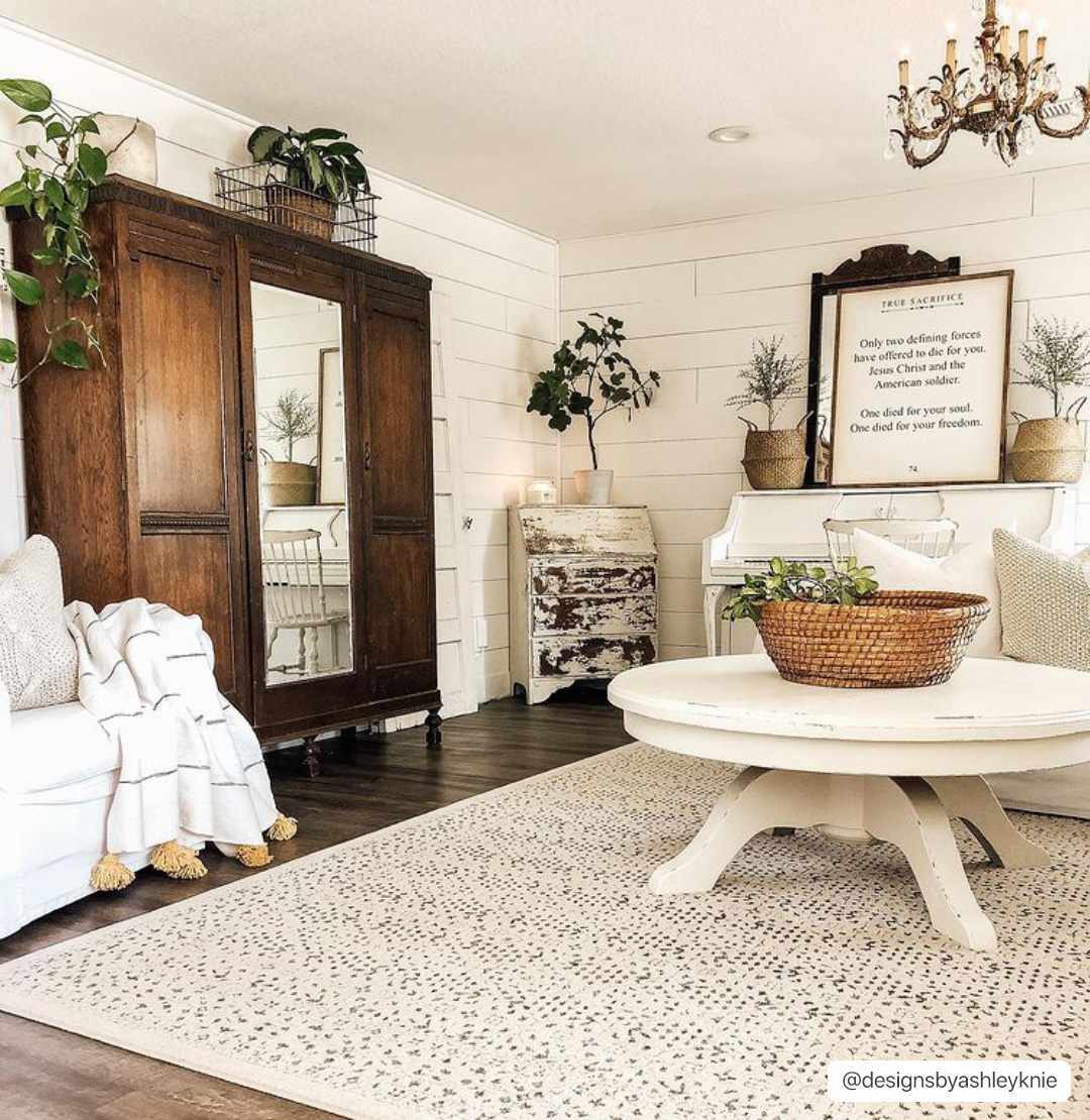 Living room with wooden armoire, white sofa, and decorative elements.