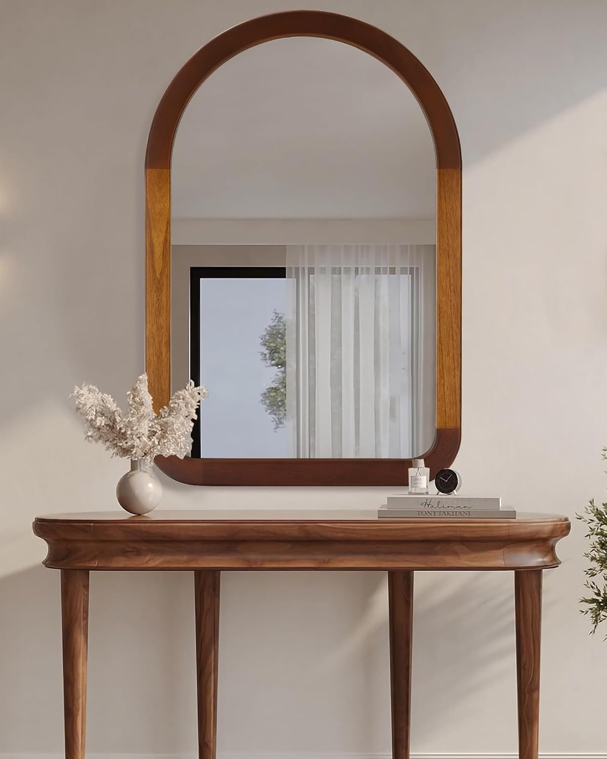 Wooden console table with a mirror and decorative items against a neutral wall.