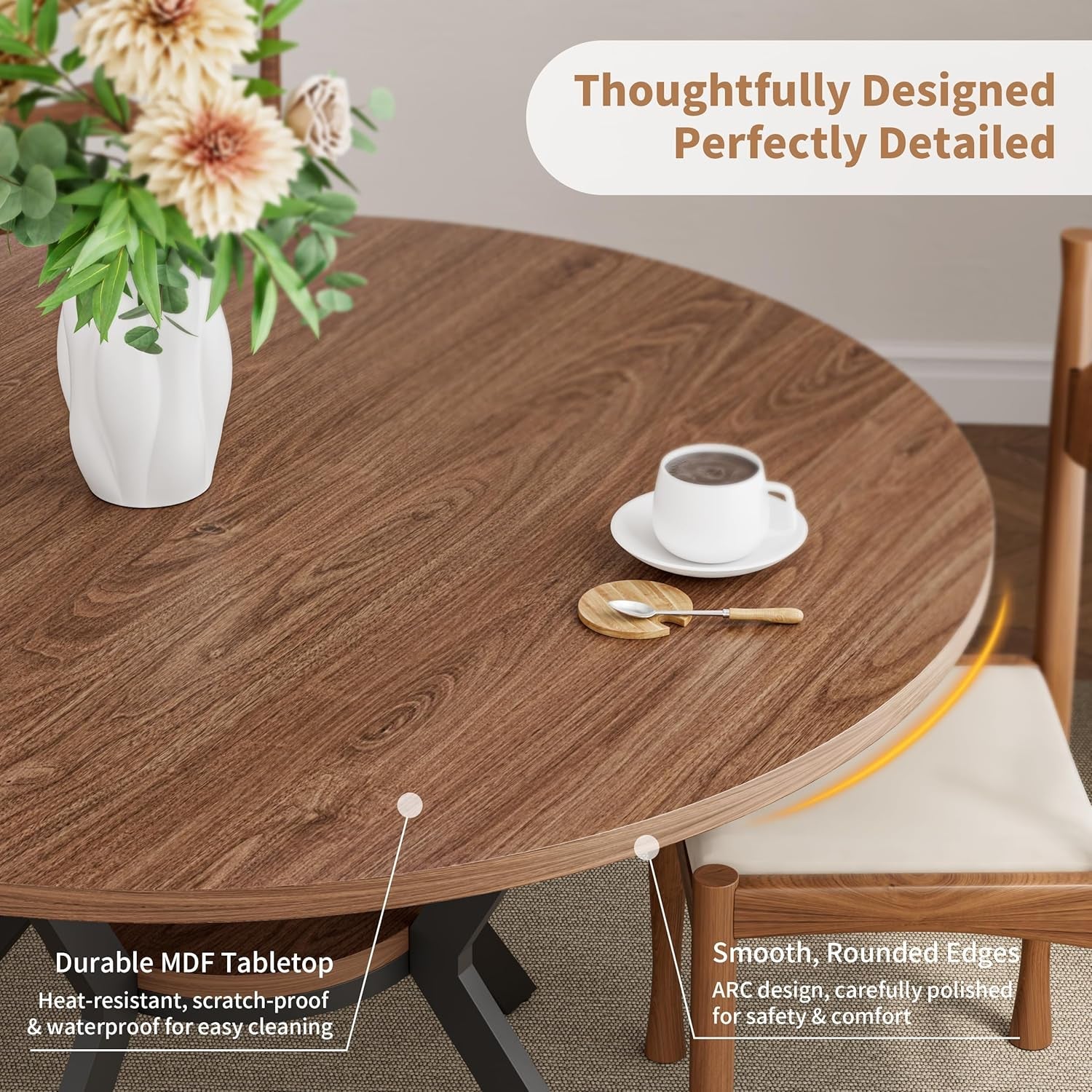 Round wooden dining table with a vase of flowers and a cup on a chair.