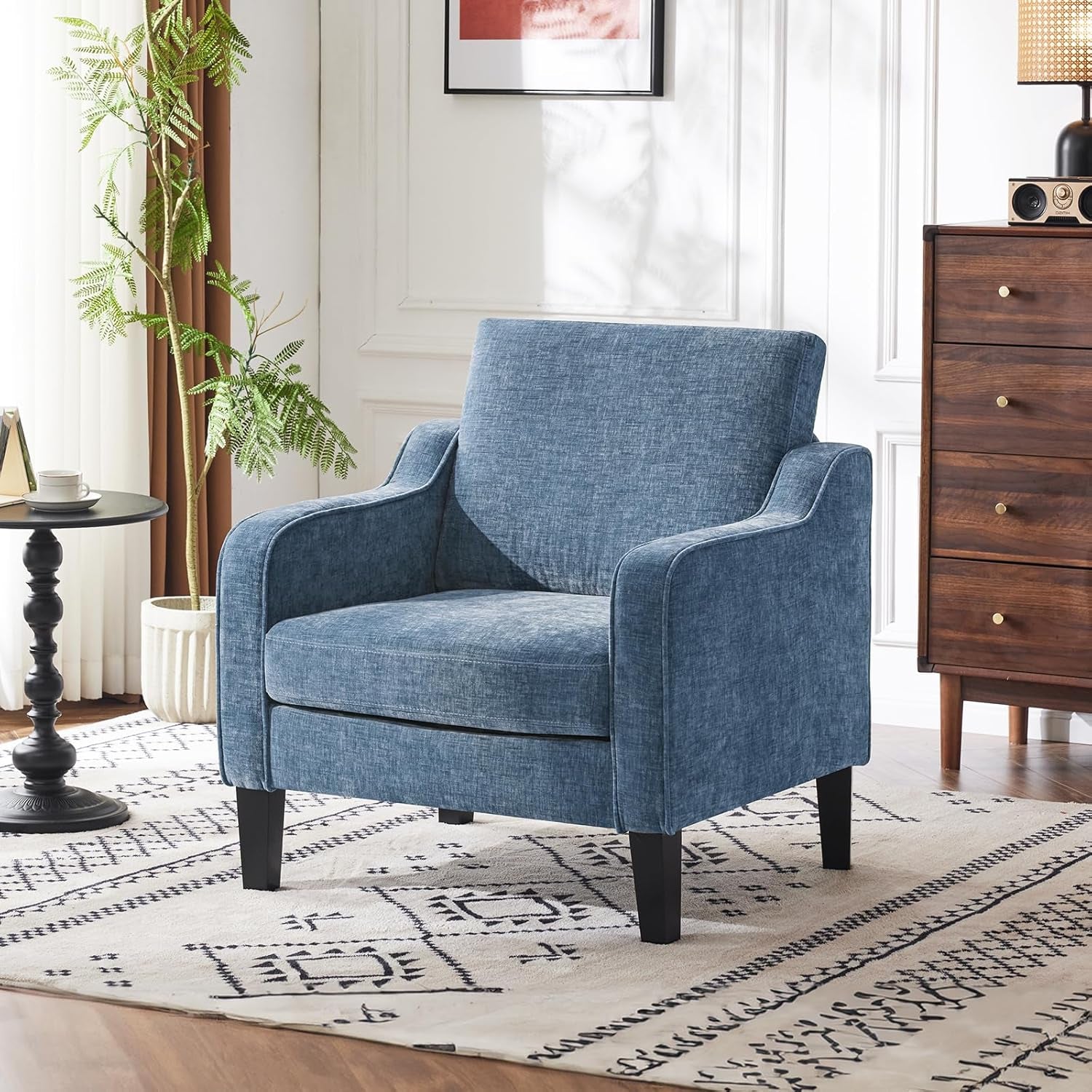 Blue armchair in a living room setting with a wooden dresser and decorative items.