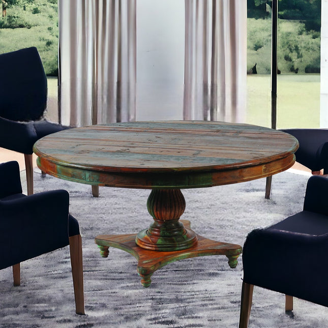 Round wooden table with a vintage design in a room with large windows and curtains.