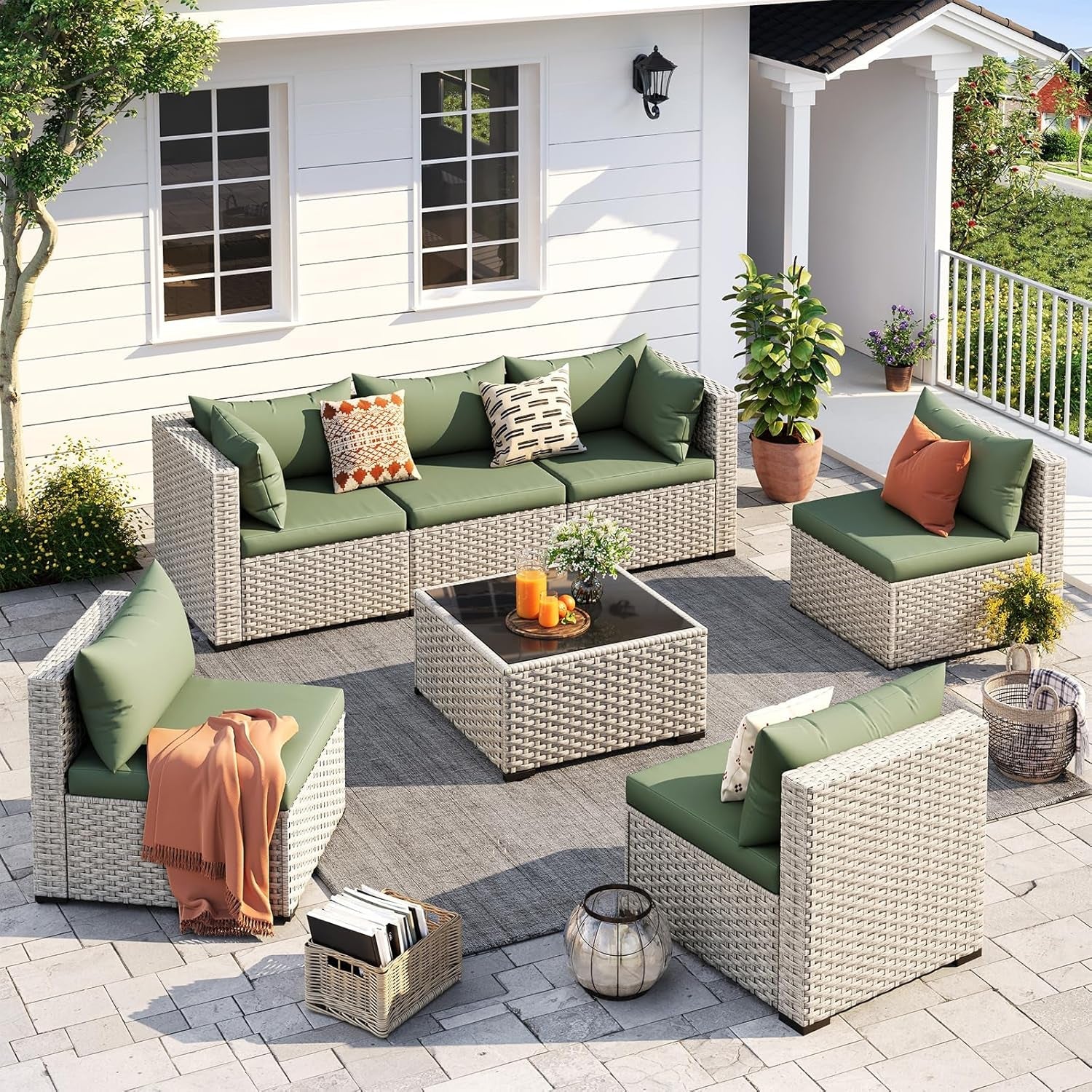 Outdoor patio furniture set with green cushions and a coffee table on a patio.