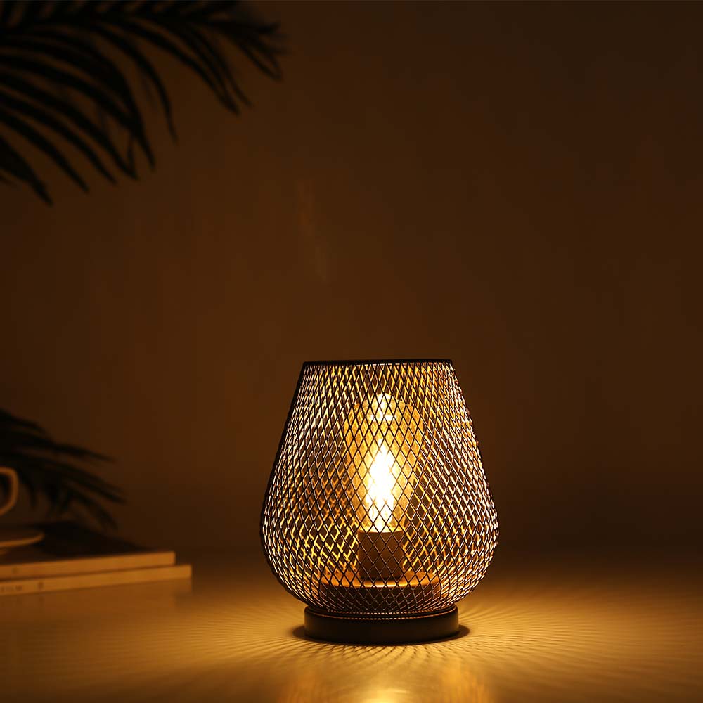Woven wire table lamp emitting a warm glow on a dark background