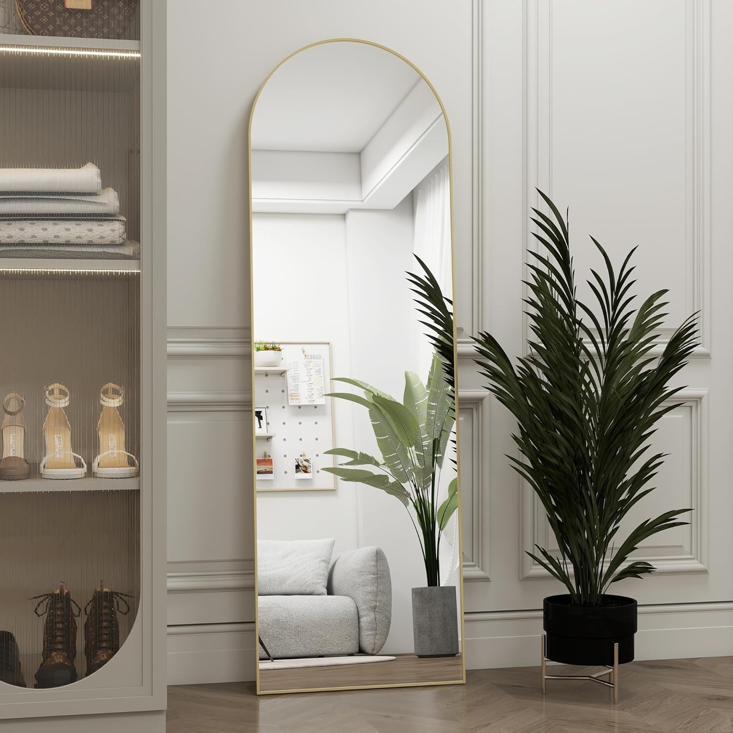 Full-length mirror in a modern interior setting with a plant and shelves.